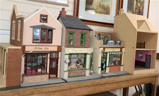 A group of three dolls house models of shops with figures and accessories and an unfinished dolls house